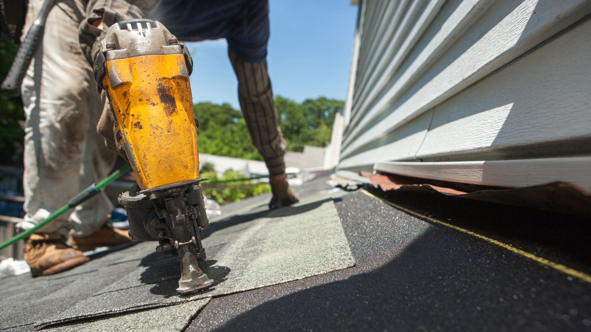 Yellow roofing nailer on shingle roof during residential construction