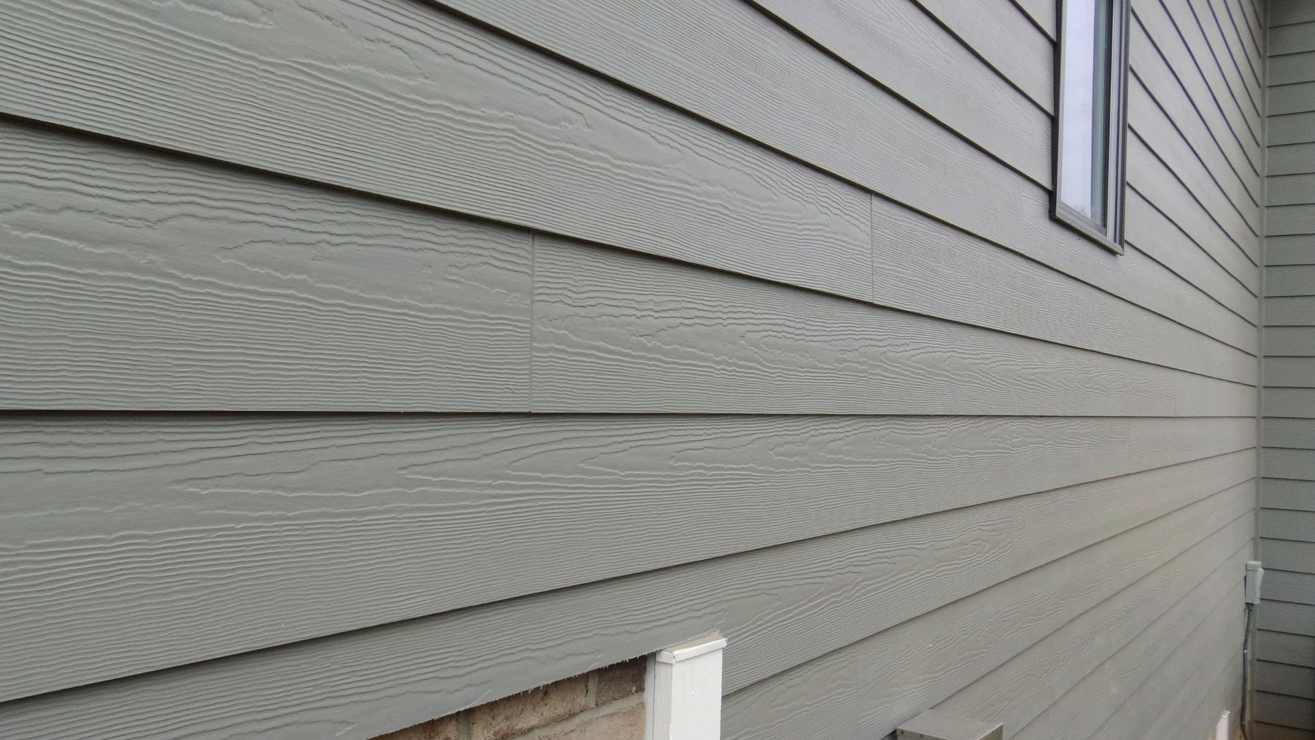Gray horizontal siding on house exterior with wood-grain texture and window