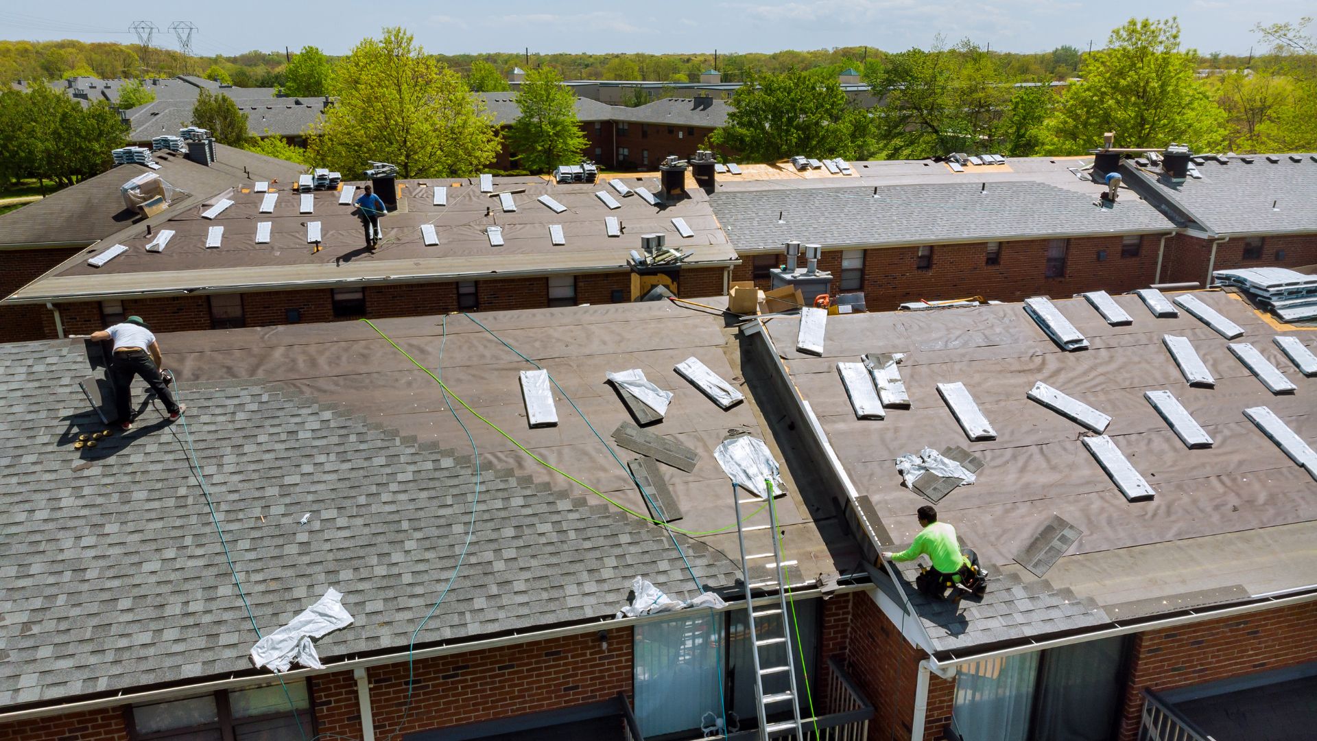 Workers installing solar panels on multiple rooftops of residential buildings