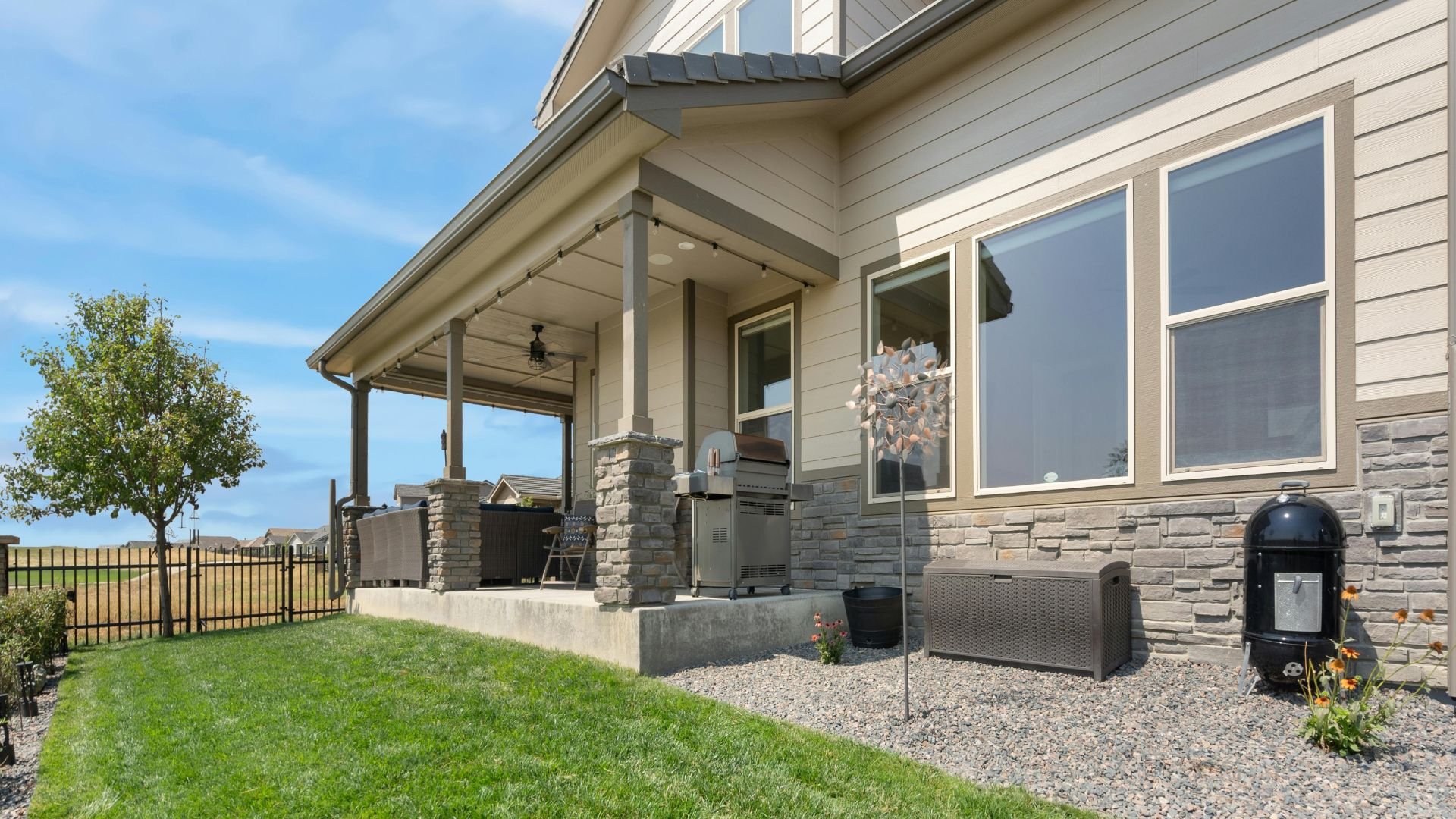 Outdoor patio with grill, covered seating area, and well-manicured backyard
