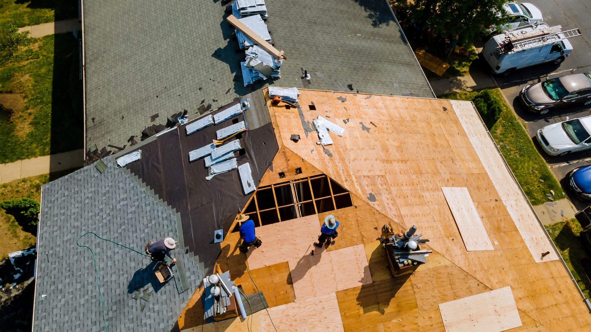 Aerial view of workers installing wooden roof shingles on residential house