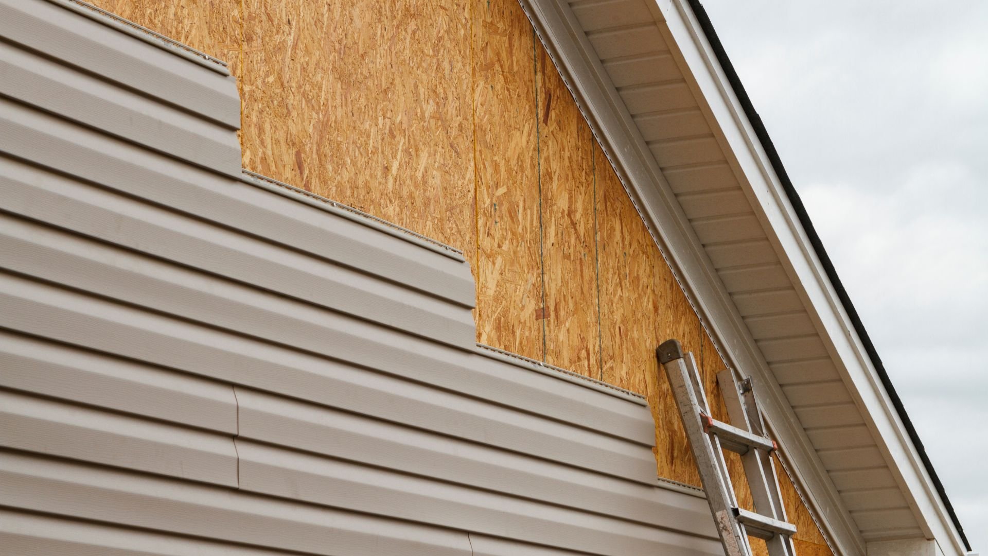 House under construction with vinyl siding and wooden sheathing and ladder